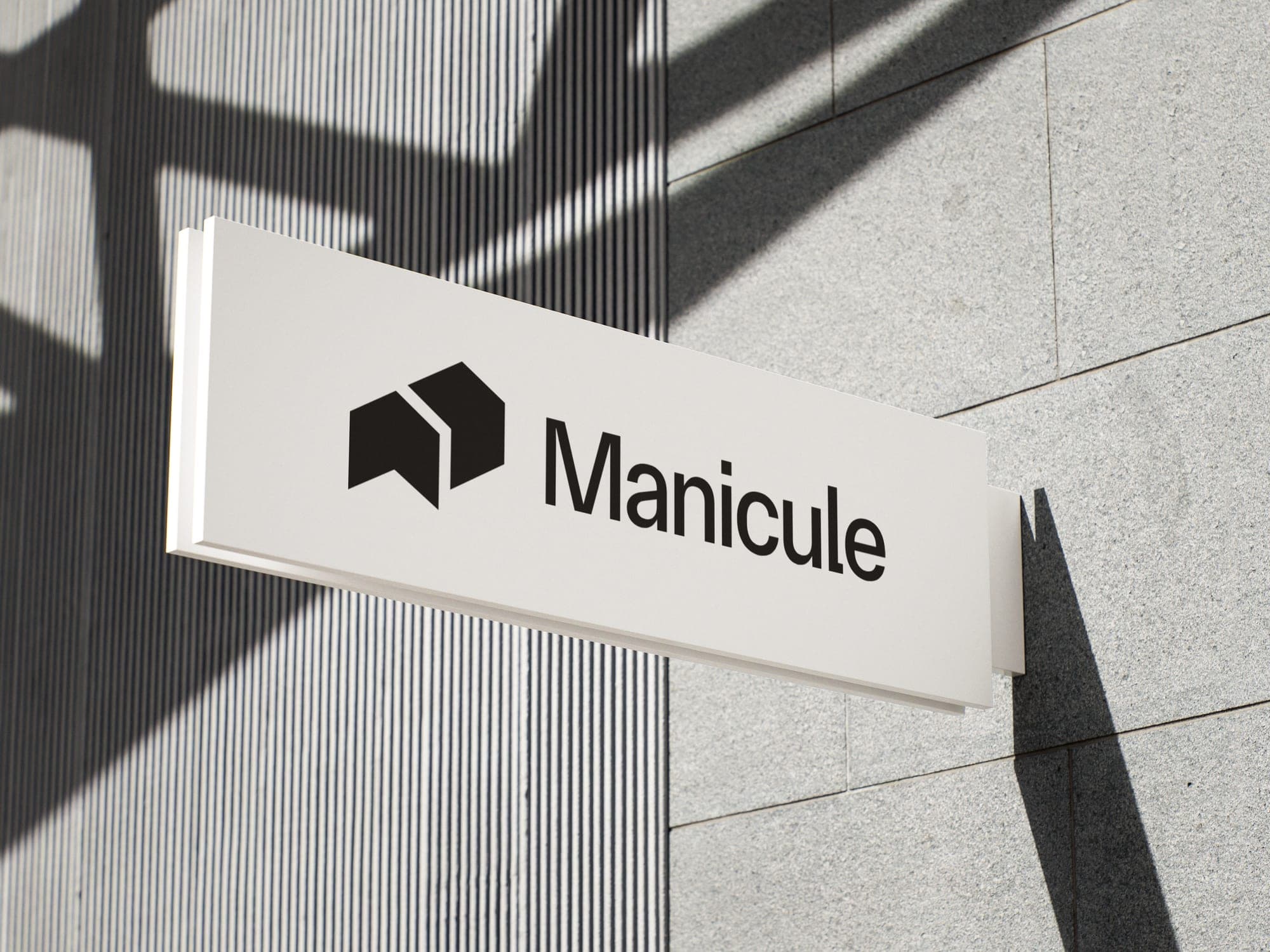 Blade sign mounted on a concrete facade with the horizontal Manicule lockup.